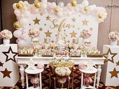 a table set up for a party with balloons and stars on the wall behind it