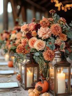 an arrangement of flowers, candles and pumpkins are sitting on a long wooden table