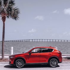 a red mazda cx - 5 parked next to the ocean