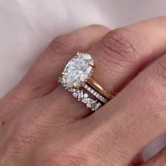 a woman's hand with a diamond ring and two wedding bands on her finger