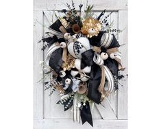 a black and white wreath with gold accents on a wooden door, decorated with flowers