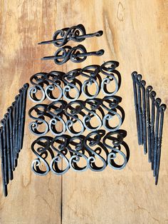 several pairs of scissors are sitting on a wooden table next to some black iron hooks