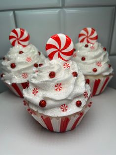 two cupcakes with white frosting and candy canes