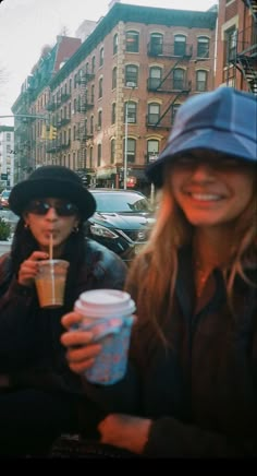 two women sitting on a bench with drinks in their hands