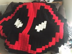 a large black and red blanket on top of a bed next to a stuffed animal