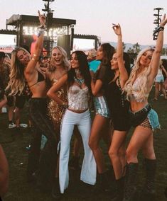 a group of women standing next to each other in front of a crowd at a music festival