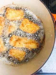 some food is cooking in a frying pan on the stove top with water and oil