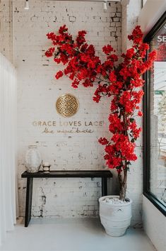 a vase with red flowers sitting next to a bench in front of a brick wall