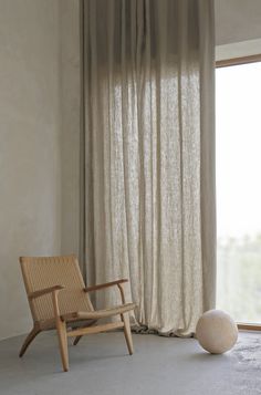 a chair sitting in front of a window next to a large white ball on the floor