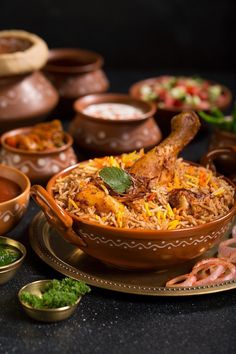 a large bowl filled with food next to small bowls and sauces on a table