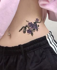 a woman's stomach with a snake and flowers tattoo on her lower back side