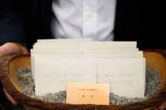 a person holding a wooden bowl filled with lots of cards and envelopes on top of it