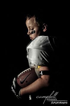 a young boy holding a football in his hands