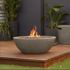 a fire pit sitting on top of a wooden deck next to potted planters