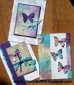 three cards with butterflies on them sitting on top of a wooden table next to each other