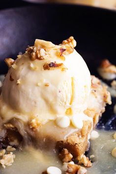 a scoop of ice cream sitting on top of a pan filled with nuts and other toppings