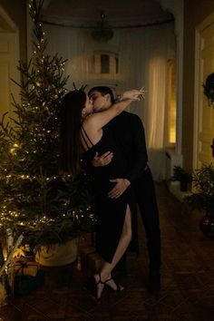 a man and woman hugging in front of a christmas tree