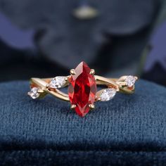 a close up of a ring with a red stone in the middle and two white stones on each side