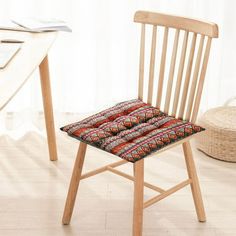 a wooden chair sitting next to a table with a laptop on it's side