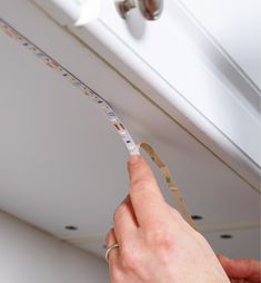 a person is measuring the length of a ceiling strip with tape on top of it