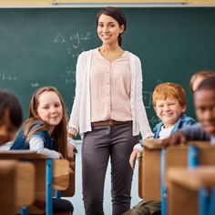 a woman standing in front of a classroom full of children with their hands on their hips