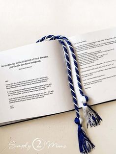 an open book with blue and white tassels