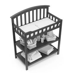 a baby crib with white sheets and blankets on the bottom shelf next to it