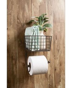 two rolls of toilet paper hanging on a wall next to a basket with a plant in it