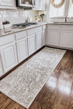 a kitchen with white cabinets and wood flooring is pictured in this image from the front view