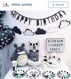 a birthday party with black and white decorations, balloons, plates and cake on a table