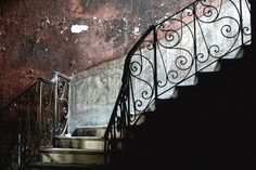 an old stairway with wrought iron handrails in front of a rusted wall