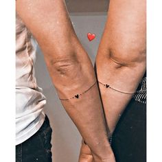 two people are holding hands with tattoos on their arms and one has a red heart