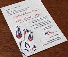 an ornate wedding card with red and blue flowers on the front, in white paper