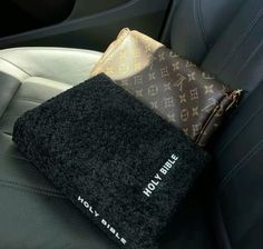 a black towel sitting on top of a car seat next to a brown and white purse