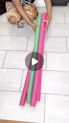 a woman kneeling down on the floor with some pink and green yoga mats in front of her