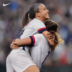 two female soccer players hugging each other on the field