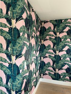 a room with pink and green wallpaper that has a large plant pattern on it