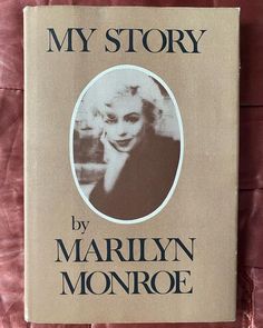 the book my story by marilyn monroe is laying on a pink sheeted surface with an image of marilyn monroe