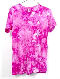 a pink tie dye shirt hanging on a white wall