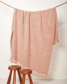 an orange and white checkered blanket hanging on a clothes line next to stools