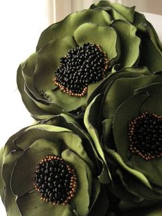 three large green flowers with beaded centers on each flower petals are shown in front of a window