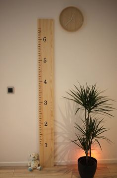 a tall wooden growth chart next to a potted plant