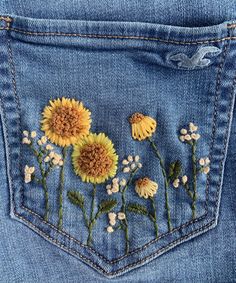 the back pocket of a pair of jeans with embroidered sunflowers and daisies