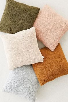 four different colored pillows sitting next to each other on top of a white countertop