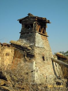 an old stone building with a clock on it's side in the middle of nowhere