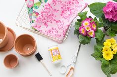 flowers and craft supplies are laid out on a white surface with pink, yellow, and purple flowers