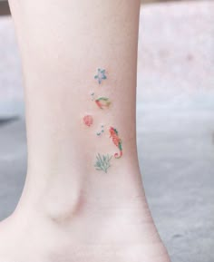 a woman's foot with small tattoos on the side of her body and flowers