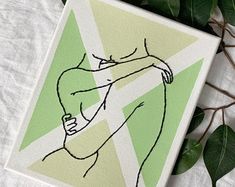 a green and white painting with a woman's torso on it next to some leaves