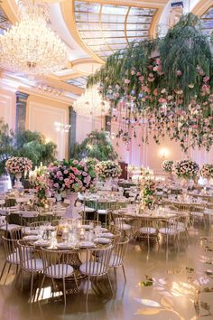 the tables are set up with flowers and greenery hanging from the ceiling above them