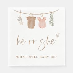 a card that says, he or she what will baby be? with clothes hanging from a line